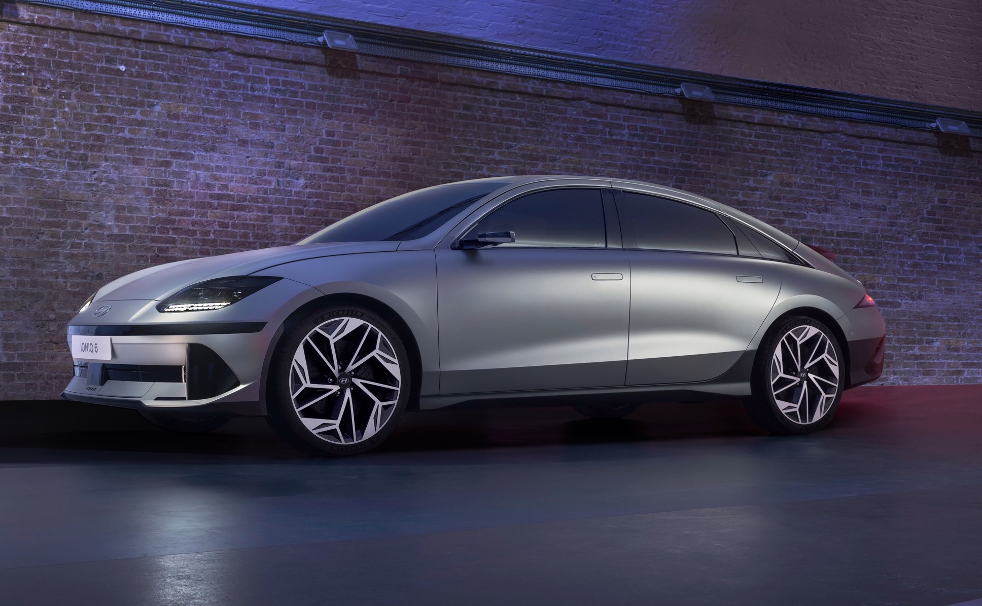 Silver Ioniq 6 side profile view indoors next to brick wall